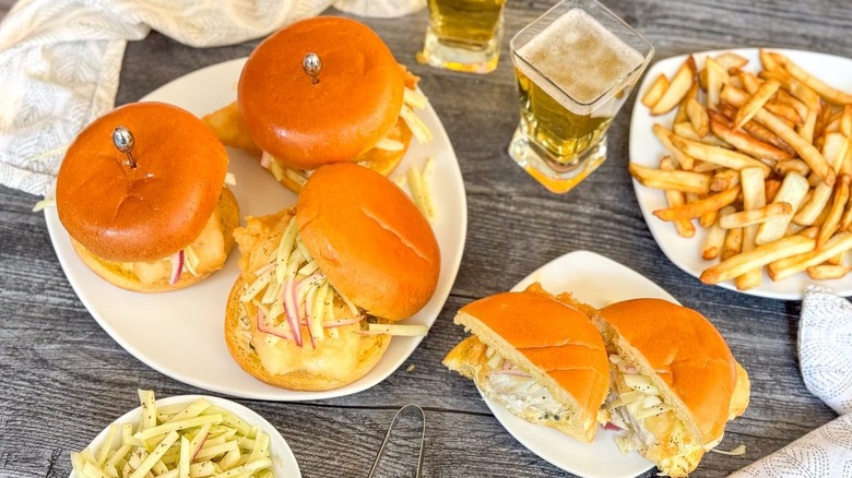 Crispy beer-battered fish sandwiches with fennel slaw on plates with beer and fries