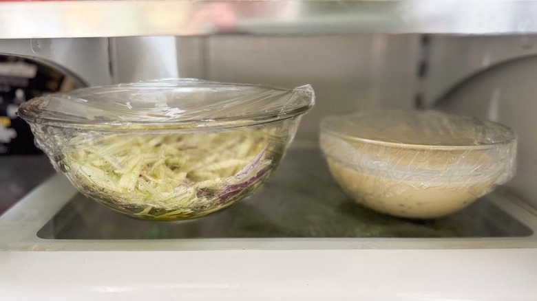 Fennel slaw and tartar sauce in glass bowls in refrigerator