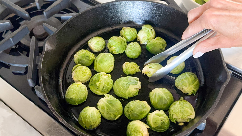 hand picking up sprout with tongs