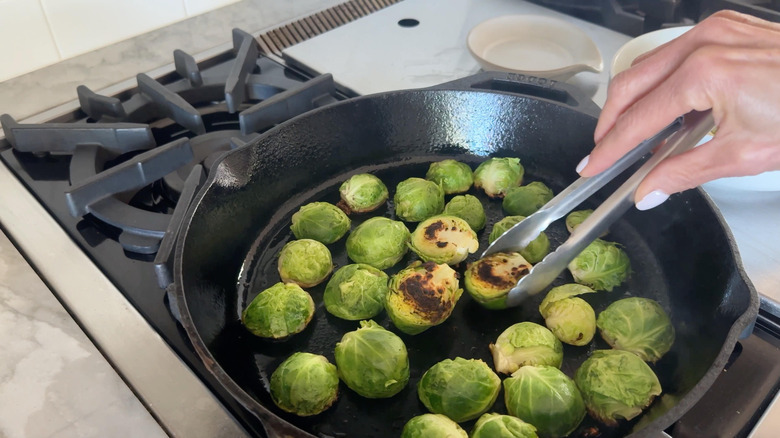 hand flipping sprout in pan