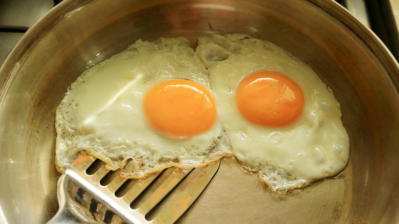 Closeup on a pair of eggs being fried in a pan.