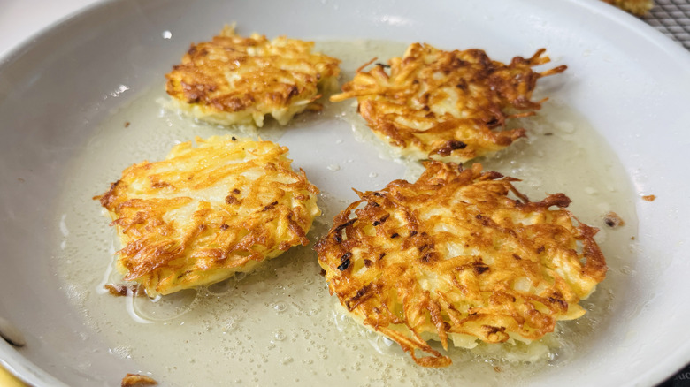 Latkes cooking in a skillet