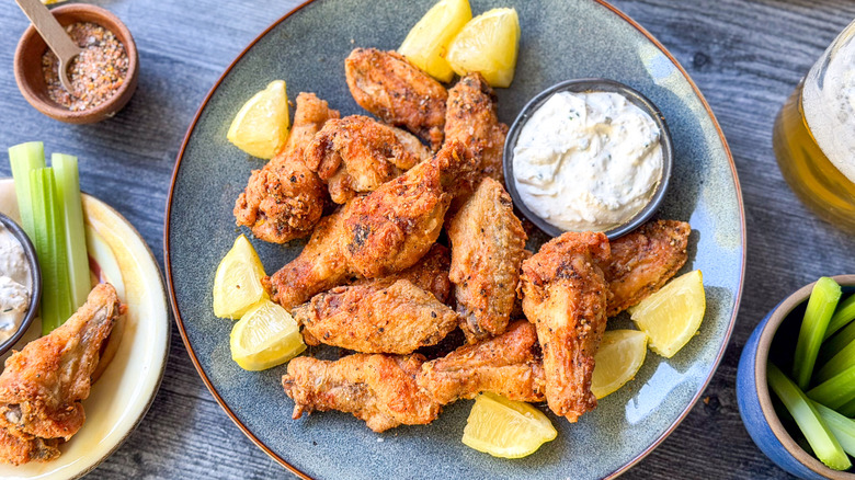 Crispy lemon pepper chicken wings with creamy feta dipping sauce on platter with lemon wedges