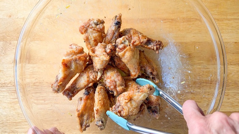 Sprinkling roasted and glazed chicken wings with dry rub