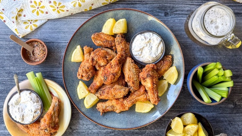 Crispy lemon pepper chicken wings on plater with garnishes and creamy feta dipping sauce