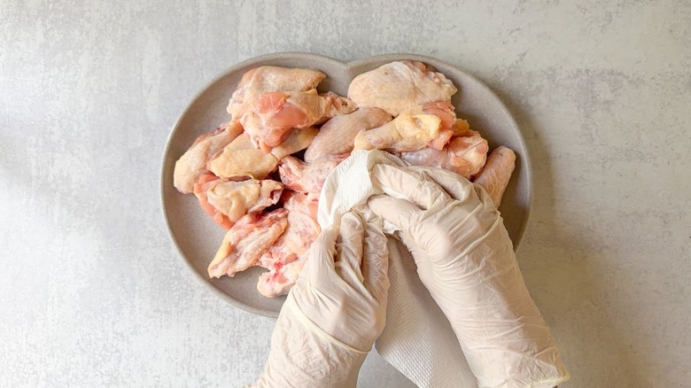 Blotting chicken wings dry with paper towels