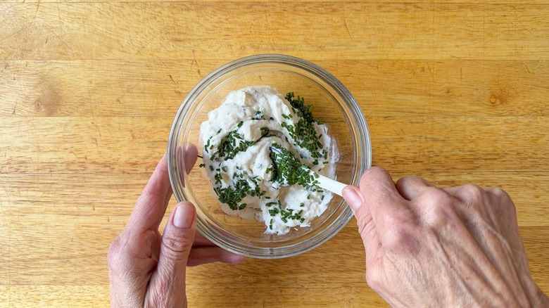 Stirring chopped chives into creamy feta dipping sauce