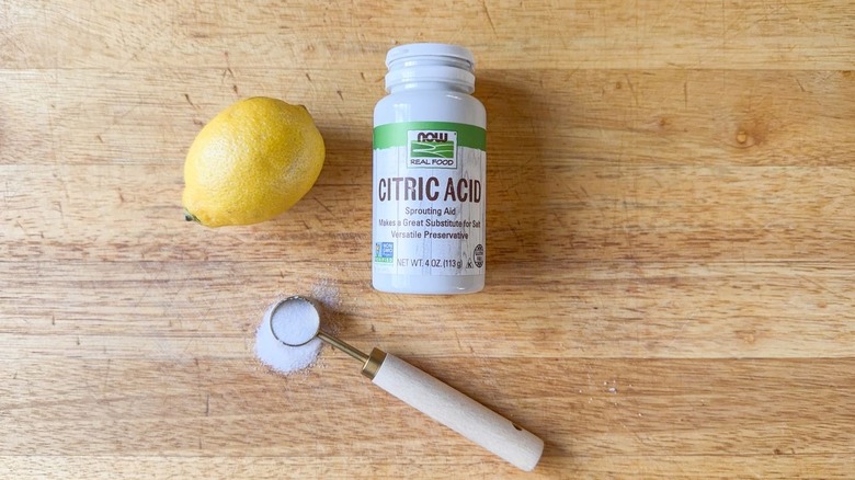 lemon, teaspoon measure, and bottle of citric acid on cutting board