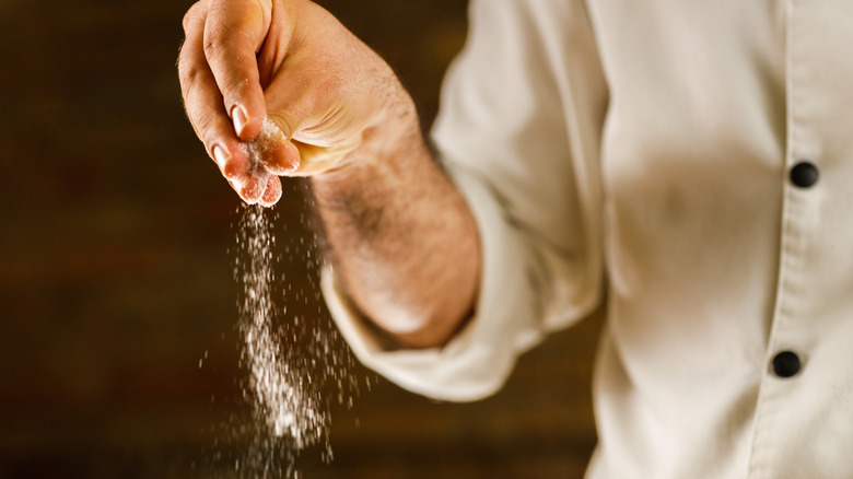 Chef adding salt to dish