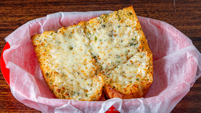 Two pieces of garlic bread in a red basket