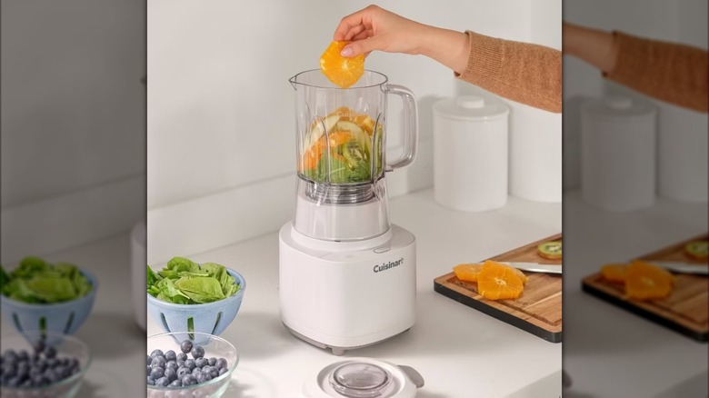 Person putting orange slice in a Cuisinart Soho blender