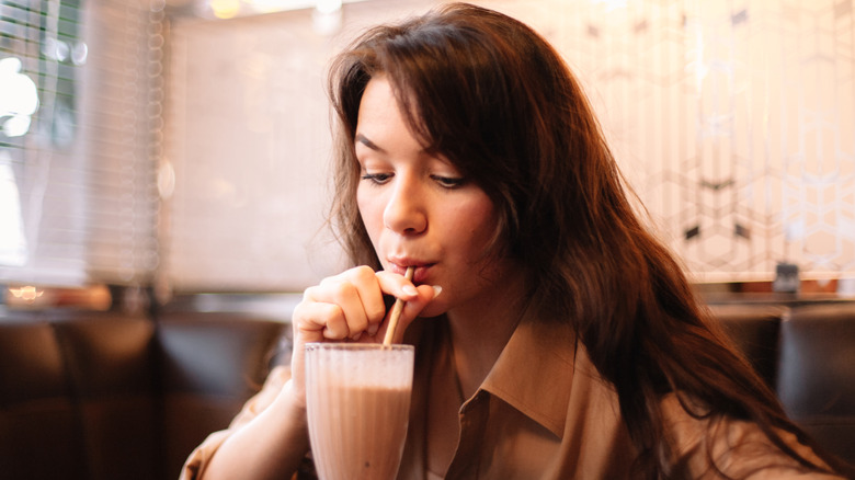 Woman drinking a chocolate milkshake from a glass
