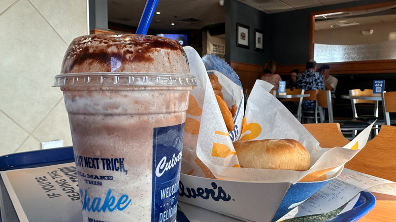 Chocolate milkshake and a burger basket on a tray table at a Culver's fast food restaurant.