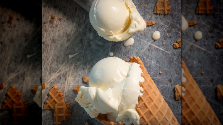 Vanilla custard in a waffle cone with a scoop of vanilla custard next to it on a slate surface