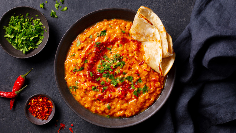 A lentil daal surrounded by seasonings and aromatics.