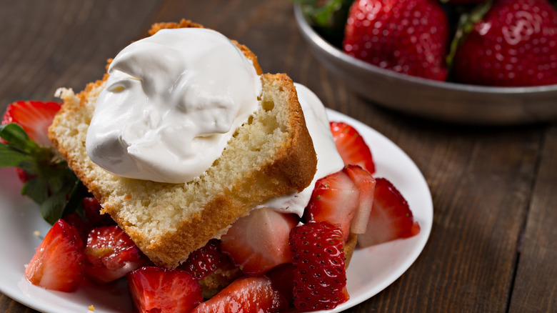 Pound cake is plated with strawberries and whipped cream.