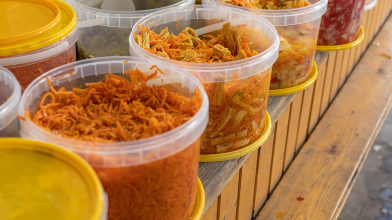 A Korean market stall with tubs of pickled carrots and cabbage