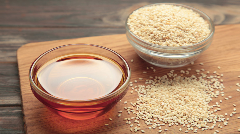 Sesame oil in a bowl surrounded by toasted sesame seeds