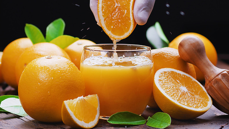 Oranges being freshly squeezed into a glass