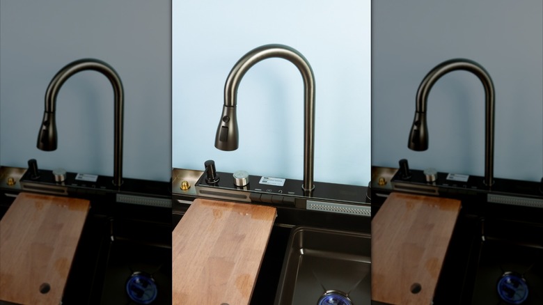 A wooden cutting board over a matte black sink