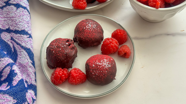 Raspberry chocolate truffles with fresh raspberries on plate