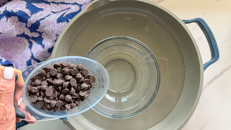 hand adding chocolate to bowl