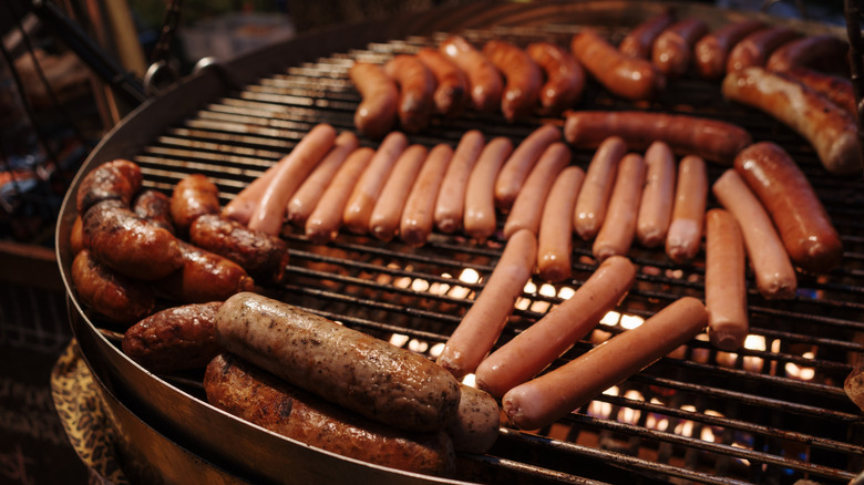 A bunch of hot dogs and sausages being cooked on a grill