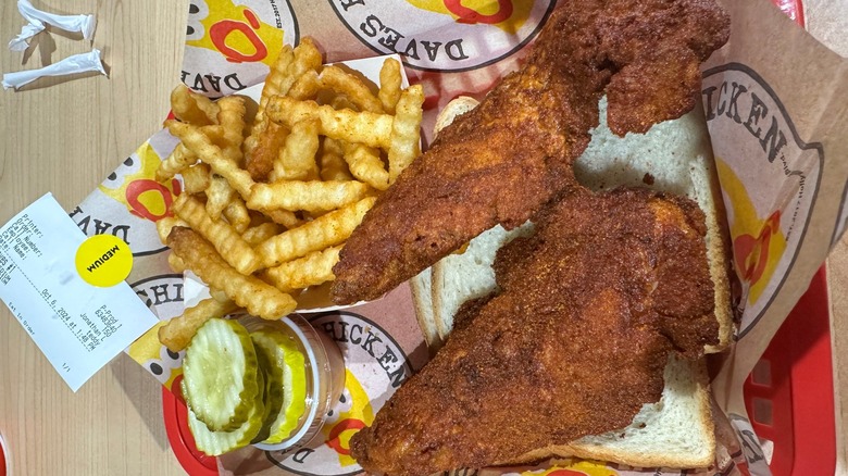 A basket of Dave's Hot Chicken over white bread, with fries
