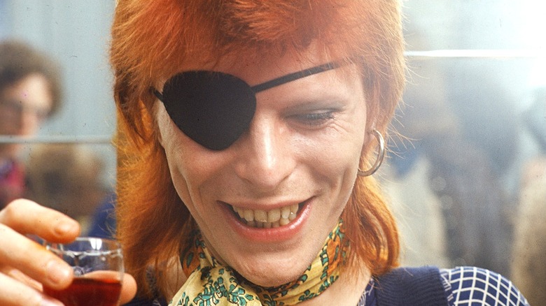 David Bowie smiling and holding a glass of wine