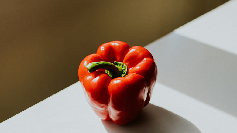 Red bell pepper on a white surface with a gold background
