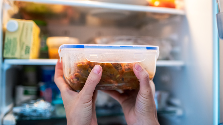 holding leftovers in front of fridge