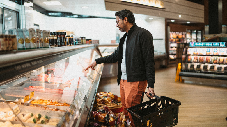 Man pointing at a supermarket deli case