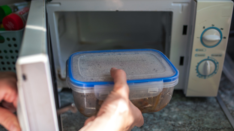 Hand placing food into a microwave