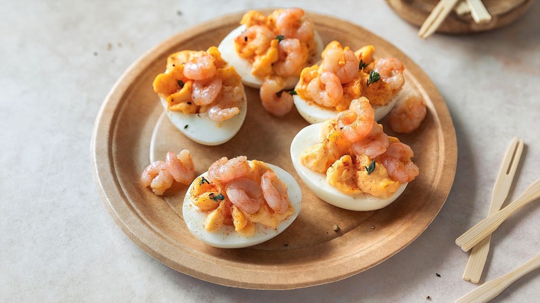 Deviled eggs with baby shrimp on a brown disposable plate