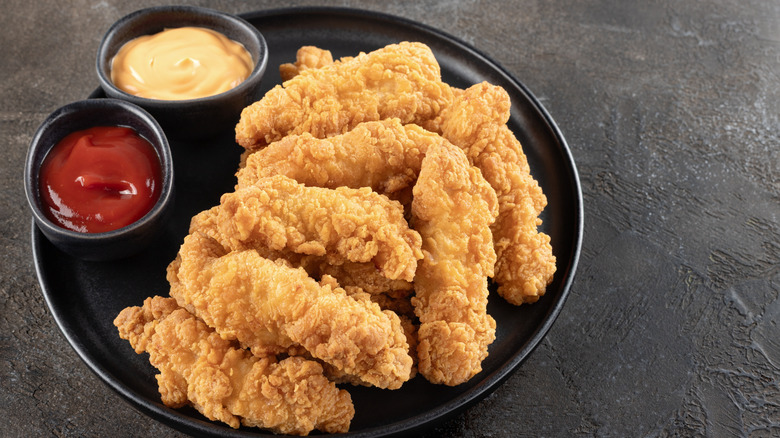 Chicken tenders on a plate with sauce.