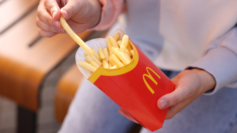 Person pulling a fry from a package of McDonald's French fries