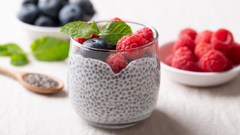 a cup of chia pudding topped with raspberries, blueberries, and mint