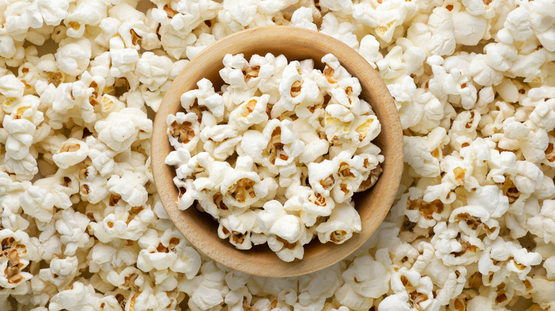 a top view of wooden bowl of popcorn on a background with more popcorn