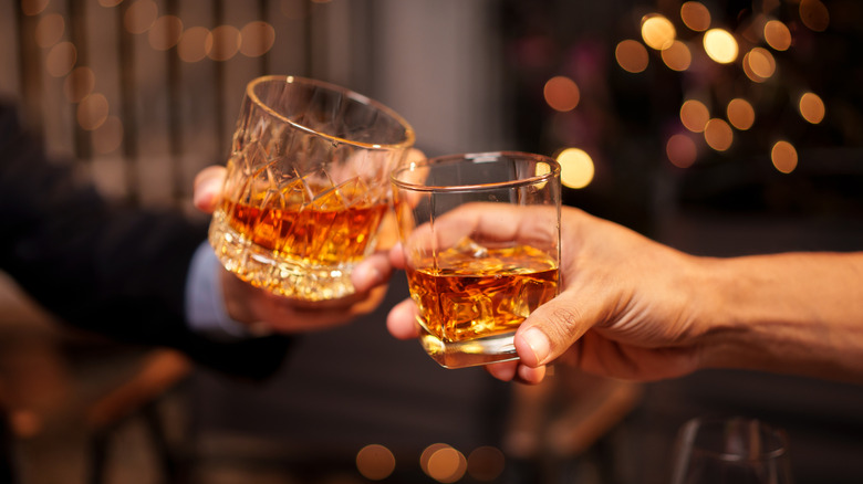 Hands clinking whiskey glasses