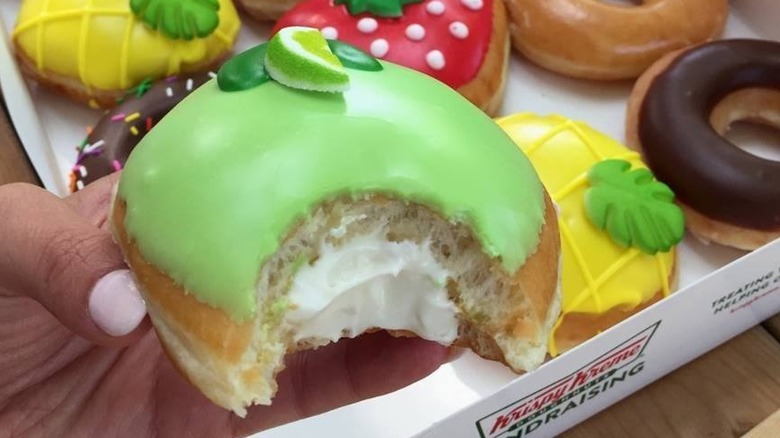 A man holds Krispy Kreme Key Lime Pie doughnut in hand