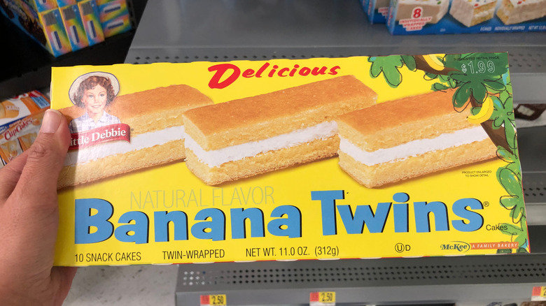 A hand holds a box of Little Debbie Banana Twins.