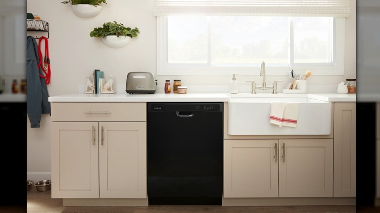 Black Amana dishwasher installed in a kitchen with tan cabinets and white countertops