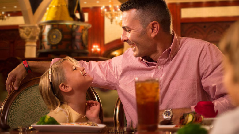 A father and daughter smiling at each other at a restaurant