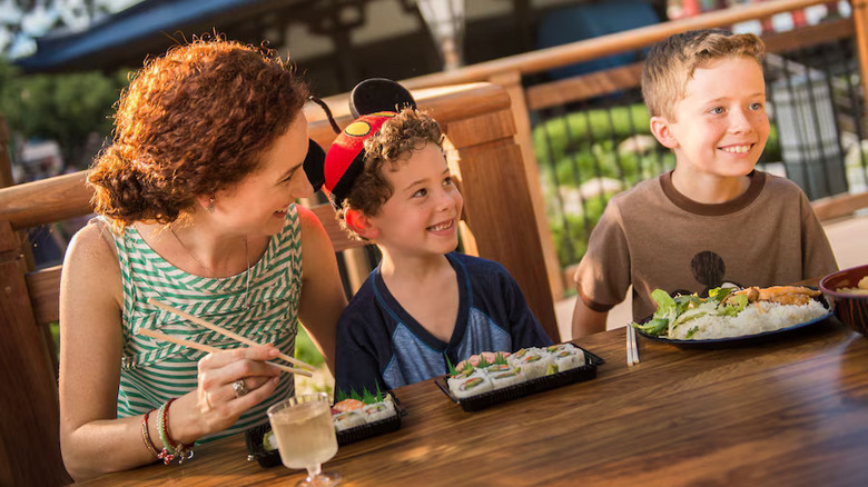 A mom eating sushi with her kids at Disney