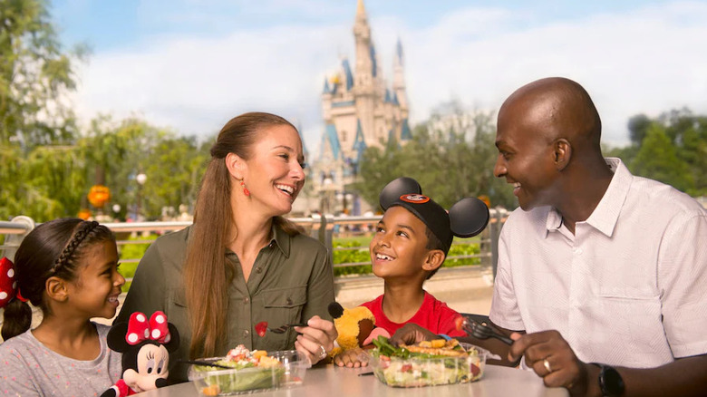 A family eating with Cinderella castle in the background