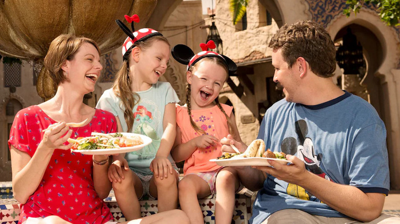 A family of four laughing and enjoying a meal together at Disney World