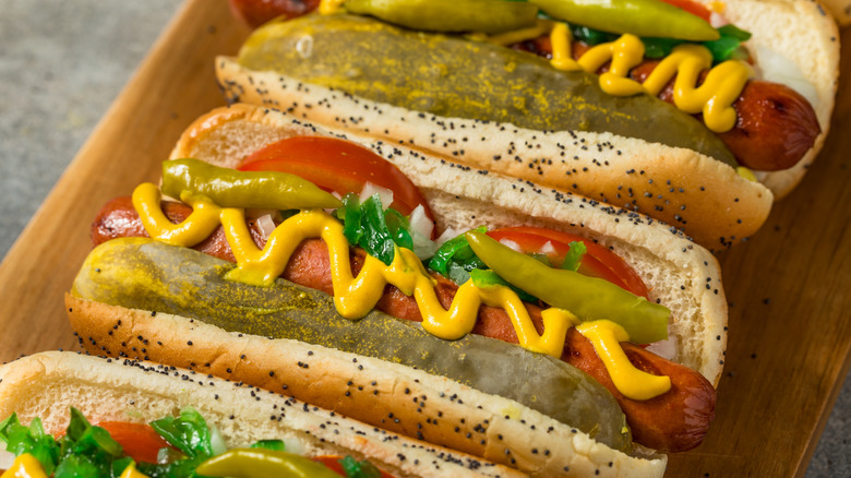 Hot dogs with pickles and mustard in seeded buns.
