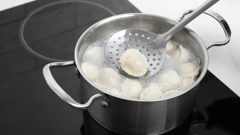 removing ravioli from boiling water with slotted spoon