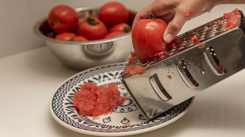 Grating tomato onto a plate with a box grater