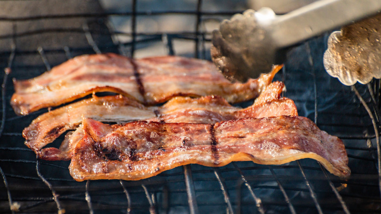 Cooking bacon over a fire.